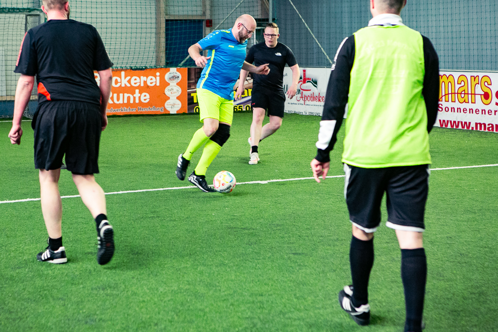 Spieler auf dem Fußballfeld kicken den Ball über den Kunstrasen der Bolzarena.