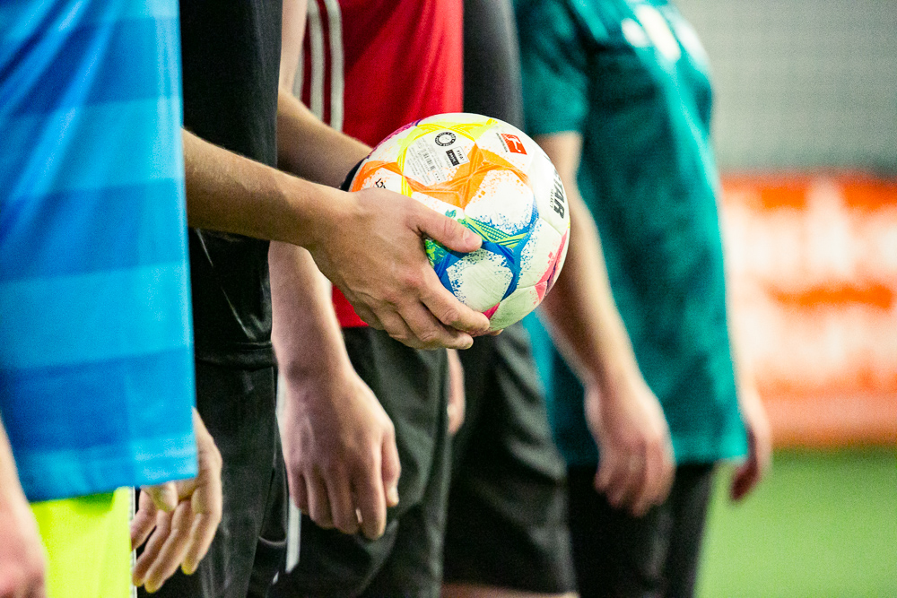 Fußballer stehen nebeneinander und einer hält den Ball in den Händen.